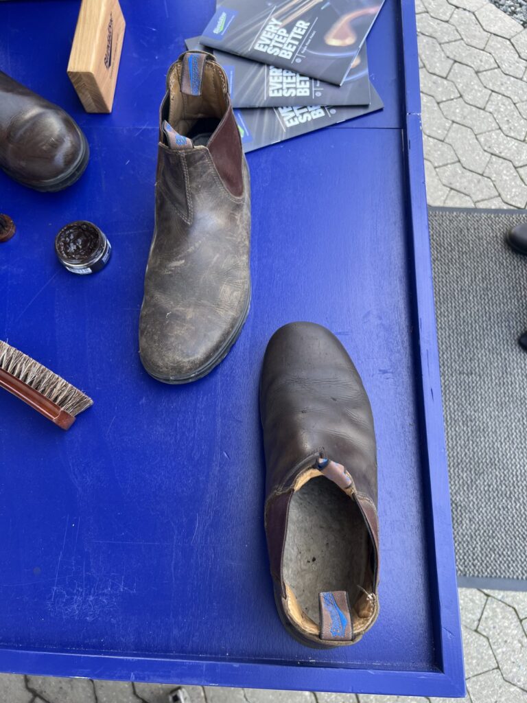 Blundstone støvle, børste og dåse med plejecreme på et bord