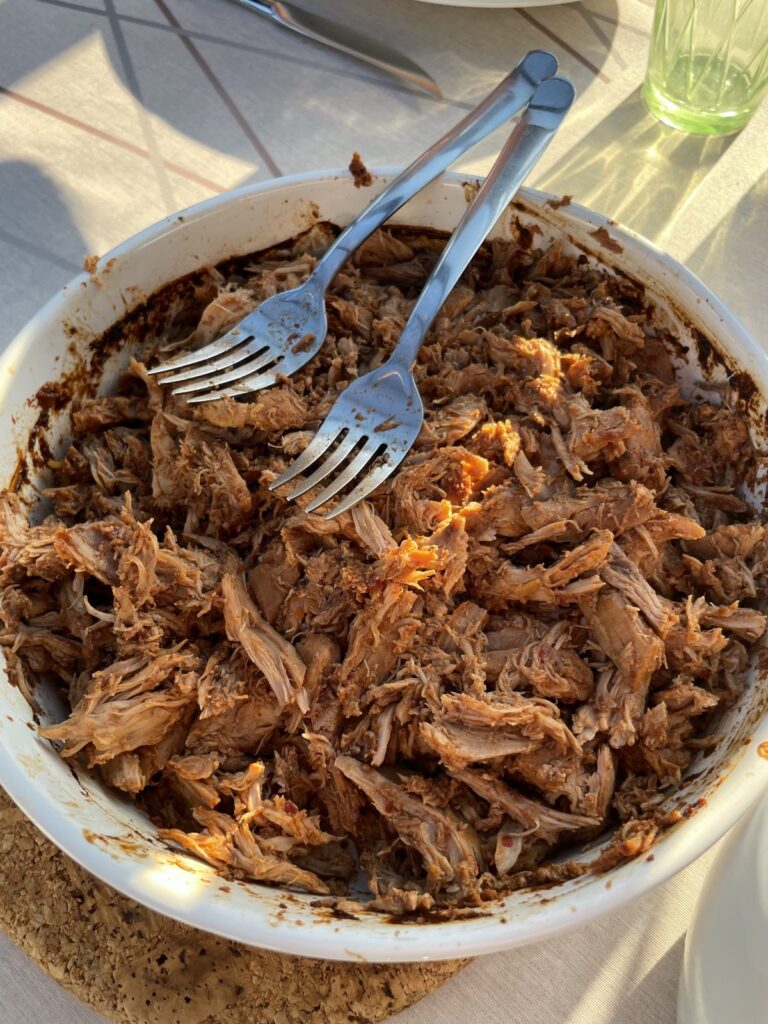 Skål med trukket fasankød vendt i BBQ-sauce og to gafler